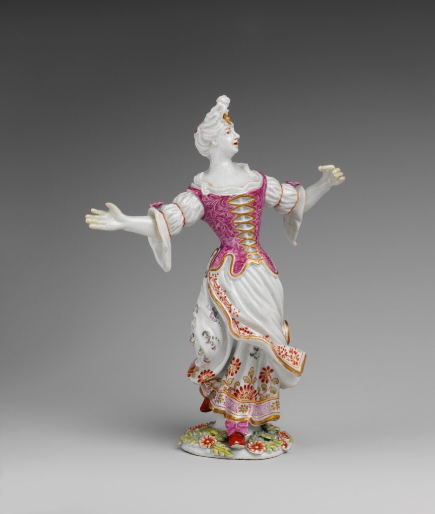 Porcelain figurine of a woman with arms outstretched in a joyful, celebratory pose.
